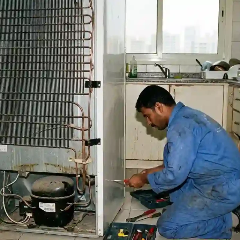 Appliance technician repairing refrigerator in Abu Dhabi home
